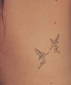 a small tattoo on the back of a woman's neck with two little birds flying around