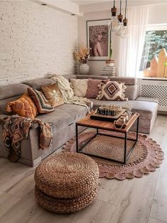 a living room filled with lots of furniture and pillows on top of a wooden floor