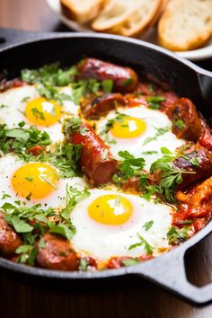 two fried eggs and sausage in a skillet with bread on the side, ready to be eaten