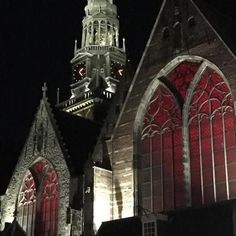 an old church lit up at night with lights on the windows and steeple in the background