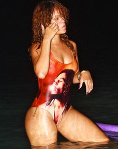 a woman in a bodysuit sitting on a surfboard