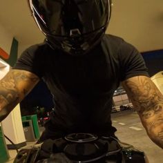 a man with tattoos on his arms riding a motorcycle