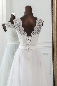 a white wedding dress on display in front of a mirror