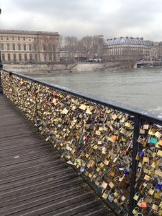 many padlocks are attached to the bridge and there is also a walkway that goes over the water