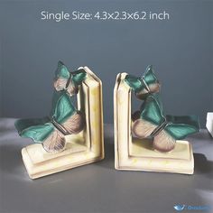 two bookends with green butterflies on them sitting next to each other in front of a gray background