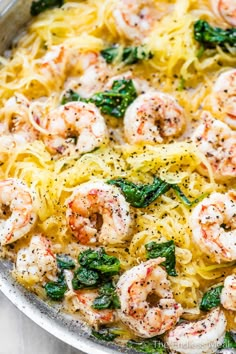 pasta with shrimp, spinach and cheese in a skillet on a marble surface