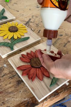 someone is painting sunflowers on wood with white paint and brown glue to make them look like they are being made out of wood