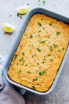 a casserole dish with parsley on top and lemons in the background