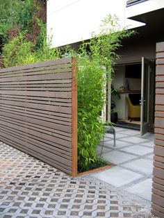 a wooden fence with plants growing on it and a building in the backround