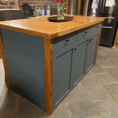 a kitchen island made out of wooden planks with flowers in a vase on top