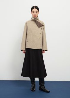 This jacket is perfectly boxy and minimal in silhouette thanks to a soft and structured layered wool melton construction. The jacket has a sleek asymmetric buttoned closure, dolman sleeves, and a mock neck collar with a folder flap detail showing a lovely tonal lining. Its unique construction pulls the right hand pocket to the front, and hides the left at the waist side. 100% wool. Model is 5ft 74 and wears size M. Modern Funnel Neck Outerwear For Fall, Chic Funnel Neck Outerwear For Work, Modern Structured Wool Coat, Asymmetrical Winter Office Outerwear, Funnel Neck Wool Outerwear For Work, Wool Funnel Neck Outerwear For Work, Wool Outerwear With Funnel Neck For Work, Modern Asymmetrical Outerwear For Work, Holiday Party Outfit