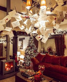 a living room filled with furniture and a christmas tree covered in notes hanging from the ceiling