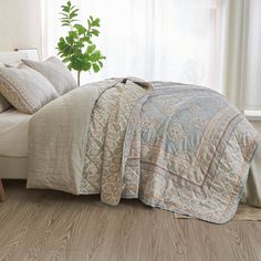 a bed sitting next to a window in a bedroom under a green leafy plant