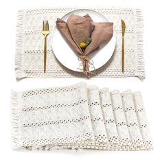 a place setting with napkins, fork and knife on a white plate next to two folded napkins