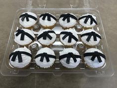 cupcakes with black bows on them in a plastic container