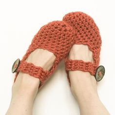 someone is wearing red slippers with buttons on the toes and their feet are crocheted