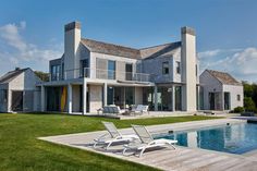 a large house with a pool in front of it and two lawn chairs next to it