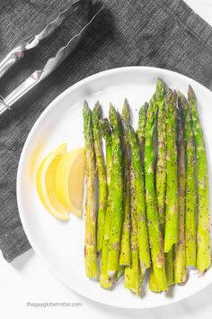 asparagus on a white plate with lemon wedges