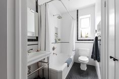 a white bathroom with black and white tile flooring