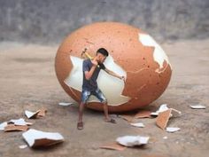 a young boy holding a baseball bat in front of an egg with torn paper on the ground