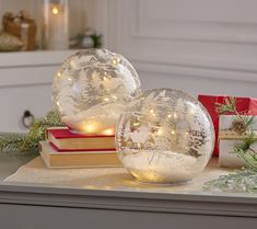 two clear glass globes sitting on top of a table next to christmas decorations and presents