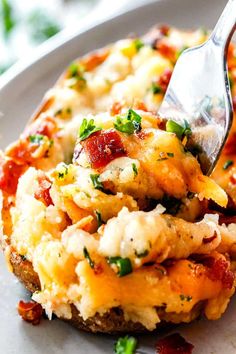 a fork digging into a cheesy baked potato casserole on a plate