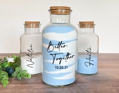 three glass bottles with writing on them sitting on a table