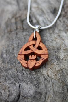 "This beautiful and unique hand-carved Irish Claddagh necklace will be made for you, or a loved one, in my studio on the West of Ireland. Adorned with a dainty Celtic silver bail, this detailed Trinity Celtic knot pendant features a piece of rosewood, recycled from musical instruments constructed by a local luthier. As a musician myself, I take enormous satisfaction in creating a necklace whose inherent wood has previously featured in a beautiful hand-made guitar. Also, part of rosewood's attrac Traditional Mahogany Jewelry As Gift, Traditional Mahogany Jewelry For Gifts, Claddagh Necklace, Irish Claddagh, Celtic Knot Pendant, Irish Gifts, Irish Heritage, Wooden Pendant, Knot Necklace