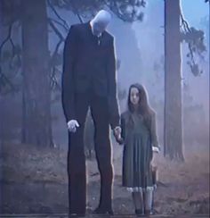 an image of a man and woman holding hands in the woods with fog behind them