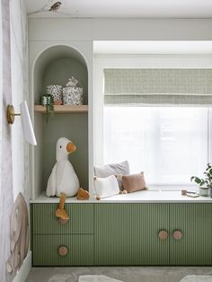 there is a stuffed duck sitting on the window sill in this green and white room