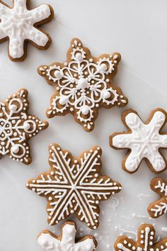 several decorated cookies sitting on top of a white countertop with icing and snowflakes