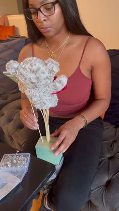 a woman sitting on a couch holding a vase with flowers in it