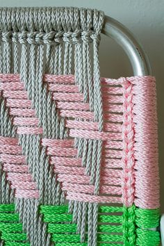 a close up of a piece of cloth on a metal frame with pink and green strips