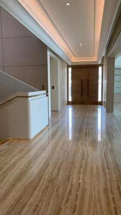 an empty room with hard wood floors and white walls, leading to a large doorway