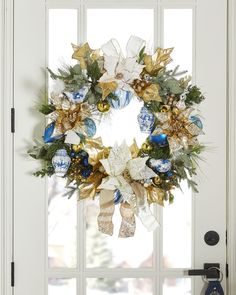 a christmas wreath is hanging on the front door with blue and gold ornaments around it