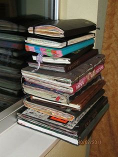 a stack of books sitting on top of a window sill