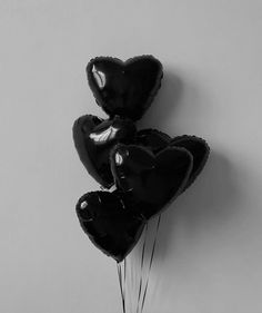 three black heart shaped balloons hanging from the wall