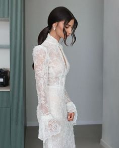 a woman in a white dress standing next to a wall