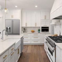 a kitchen with white cabinets and stainless steel appliances, wood flooring and gold accents