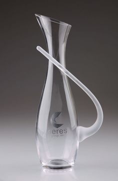 a clear vase with a curved handle on the top and bottom is shown in front of a gray background