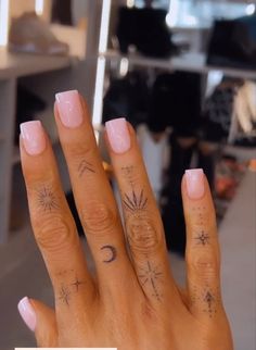 a woman's hand with tattoos on it and a pink manicured nail