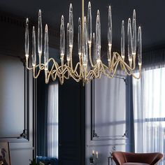 an elegant chandelier hangs in the middle of a room with blue walls and curtains