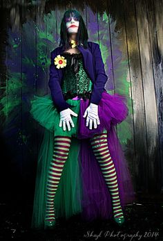 a woman dressed in green and purple posing for the camera with her hands on her hips