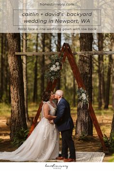 a bride and groom kissing in front of a wooden arch with greenery on it