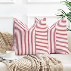 three red and white striped pillows sitting on top of a couch next to a potted plant