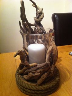 a candle is sitting in a glass with driftwood