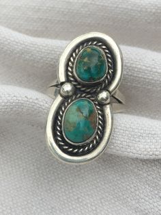 This is a beautiful example of a vintage Native American ring in an old style.  There is not a maker's mark but that is not uncommon for older pieces. It has a wonderful aged patina and will make a gorgeous statement ring. One stone looks like composite turquoise and the other is resembles Carico Lake turquoise. The face of the ring measures 1.25" long by 9/16" wide. Thank you for looking. Vintage Sterling Silver Turquoise Ring, Unique Oval Ring With Patina, Antique Sterling Silver Turquoise Ring, Vintage Hallmarked Turquoise Ring For Anniversary, Vintage Turquoise Open Ring For Anniversary, Vintage Open Turquoise Ring For Anniversary, Vintage Style Turquoise Emerald Ring For Anniversary, Vintage Sterling Silver Turquoise Ring For Anniversary, Vintage Handmade Turquoise Ring