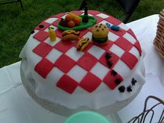 a red and white checkered cake sitting on top of a table next to a basket