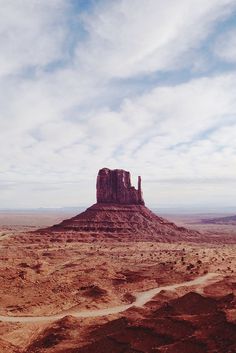 an aerial view of the desert with a rock formation in the distance and dirt roads running through it