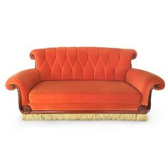 an orange couch with gold trim and fringes on the legs, sitting in front of a white background